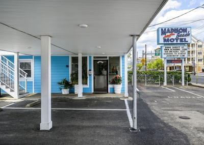 Front view of Madison Beach Motel, featuring a blue exterior, welcoming office entrance, and potted plants