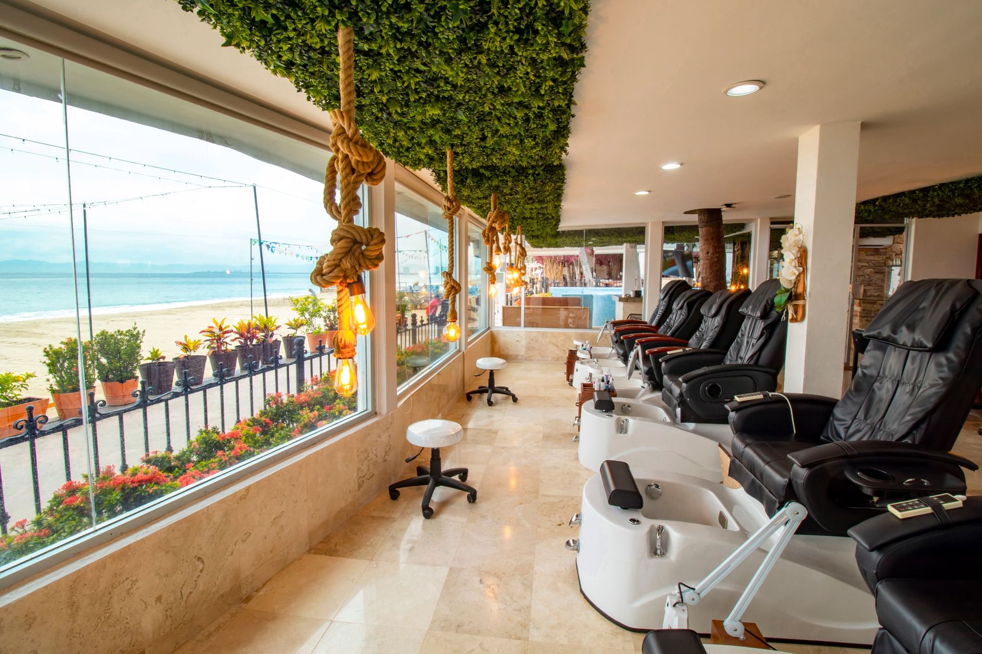 Beachfront spa salon with black pedicure chairs and ocean views at Playa Los Arcos Puerto Vallarta 2023