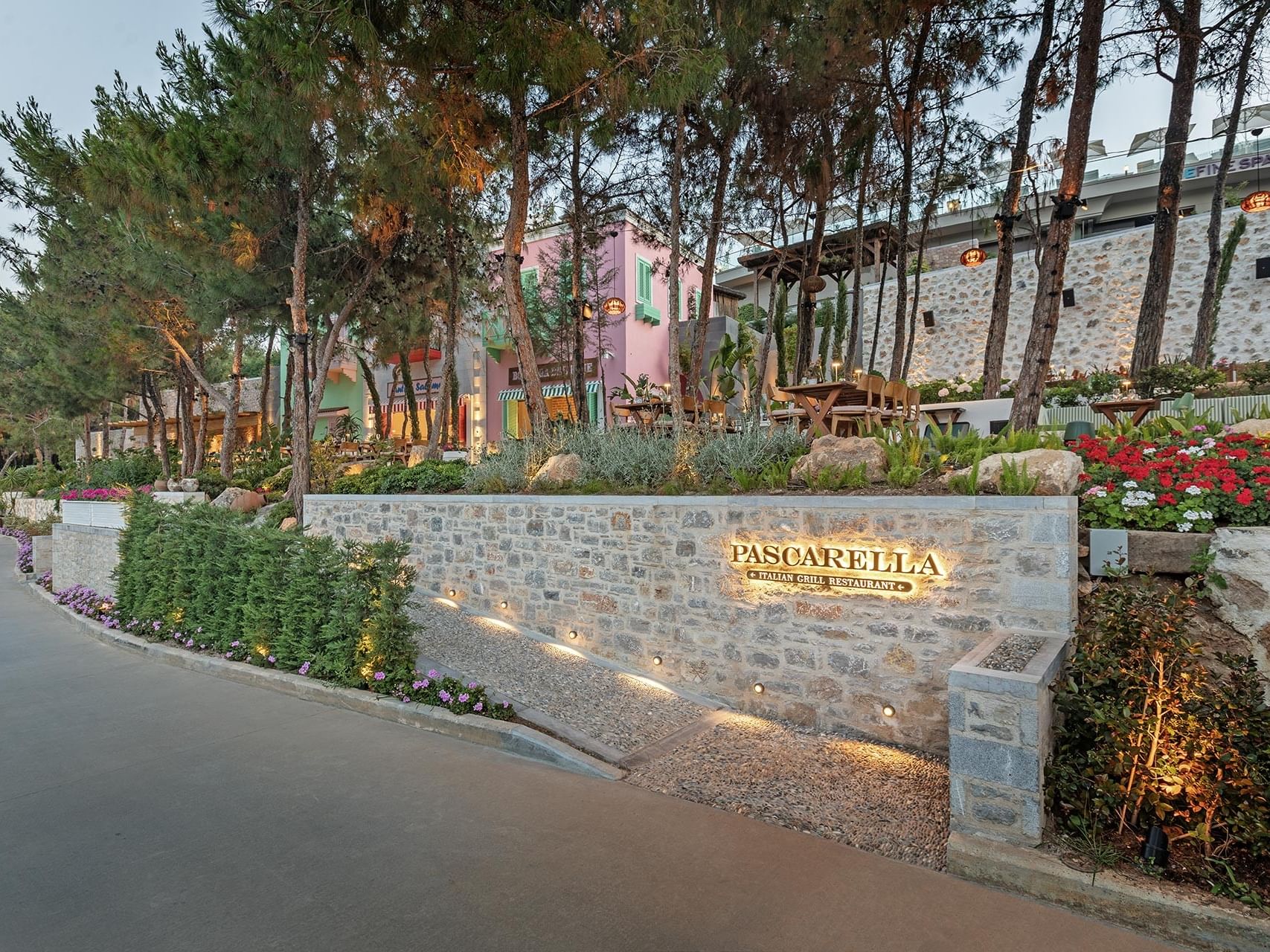 Restaurant entrance at Titanic Luxury Collection Bodrum, framed by flowers and a stone wall.