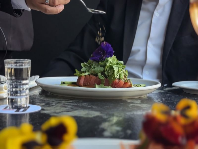Chef garnishing a tuna dish with a purple flower in La Distral Querétaro at Grand Fiesta Americana
