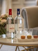 Two bottles Abatilles water & macarons by glasses on a marble table in Deluxe Suite Belle Époque at Hotel Westminster Paris