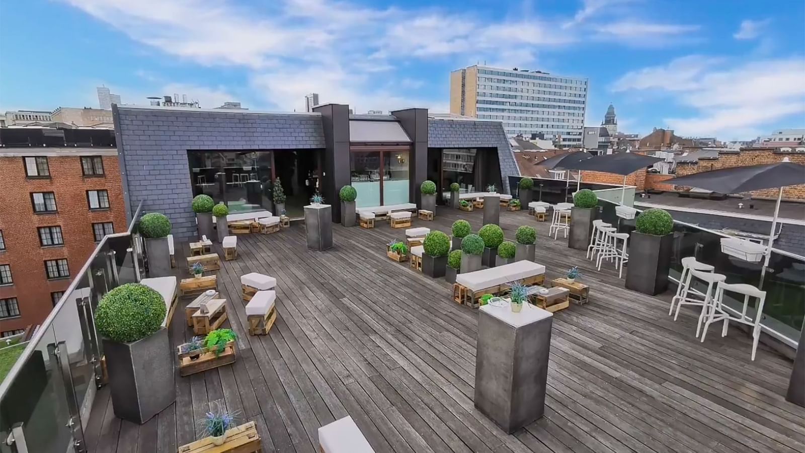 Secret rooftop terrace with white sofas placed by potted plants at Warwick Grand Place Brussels