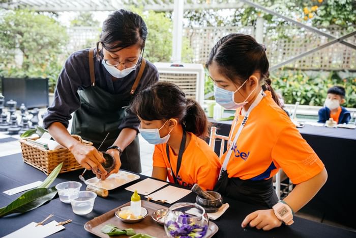 Person teaching two kids to a activity at The Fullerton Hotels and Resorts