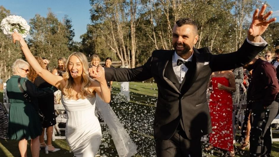 A couple walking down the aisle at an outdoor wedding ceremony with guests standing near Mercure Kooindah Waters