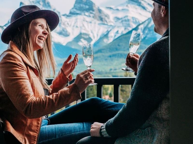 Plan ahead & Save offer featuring couple enjoying their drinks on the balcony at Malcolm Hotel