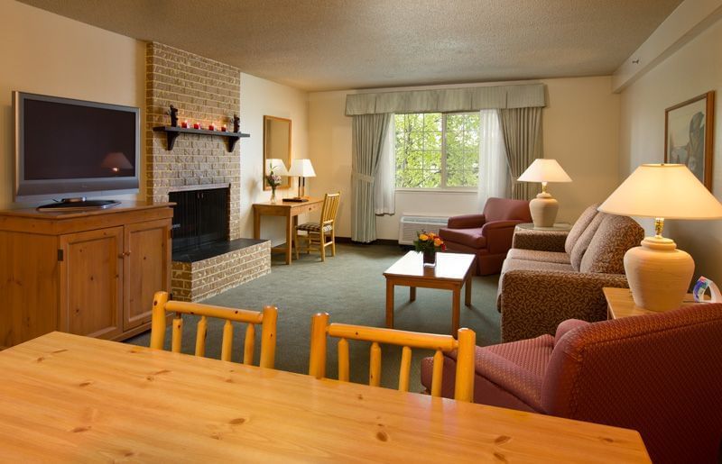 Dining table, sofa, TV, fireplace in hotel room