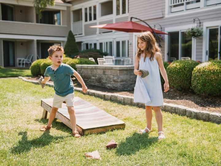 Two children playing on a lawn in front of a building.