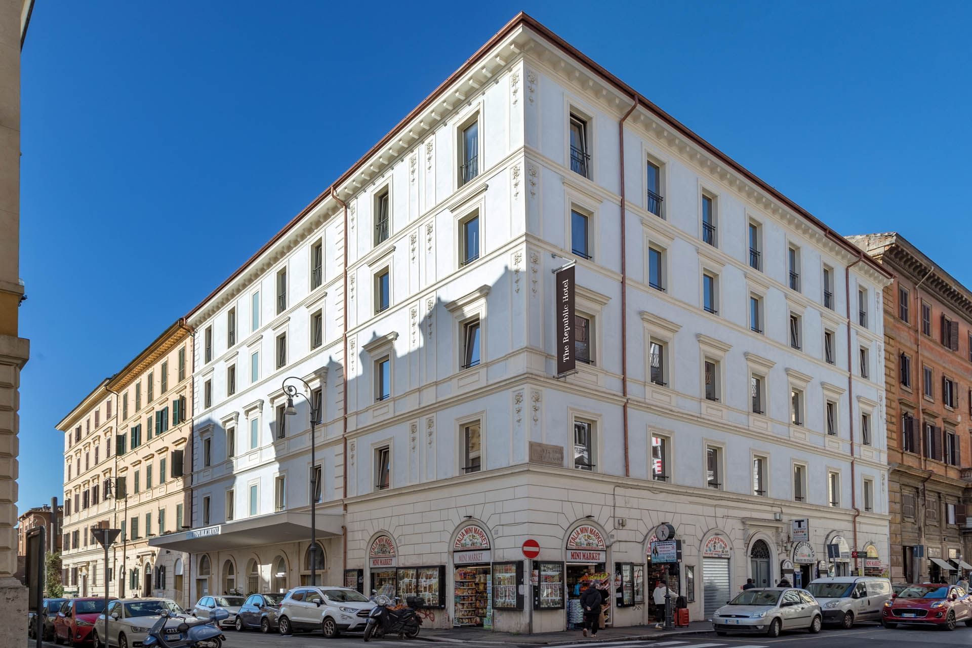 Aerial view of The Republic Hotel situated on a bustling street in Rome. Clear blue sky above.