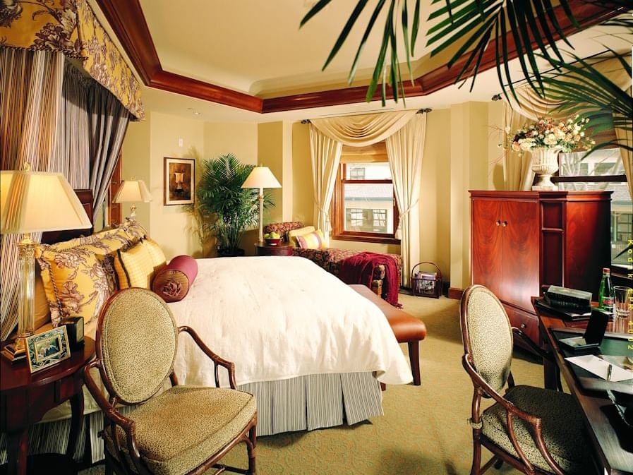 Luxurious king suite with elegant decor, classic furnishings, draped windows, and a plush bed at The Rose Hotel