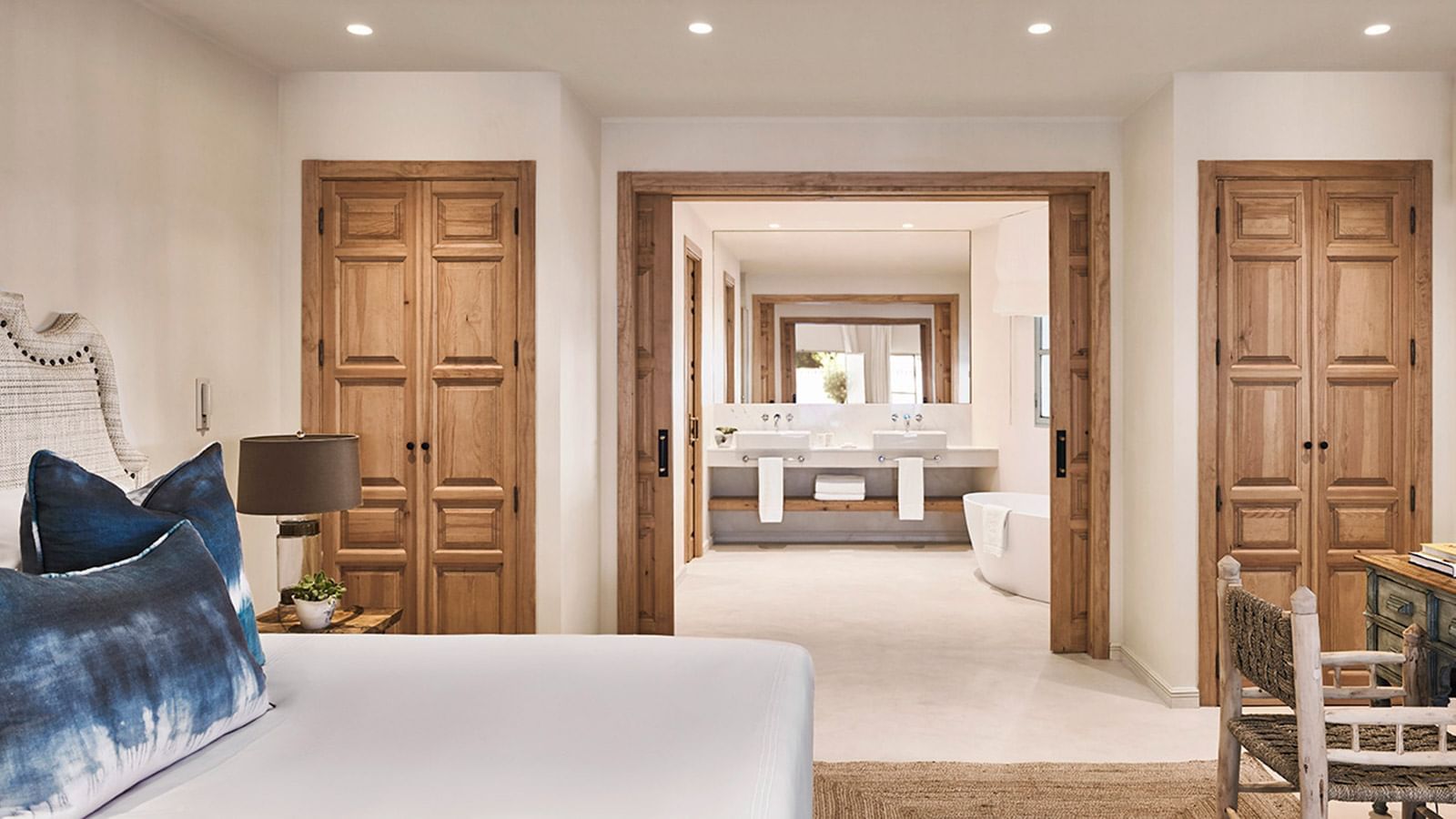 Chiquita features carved wood doors, a bed, and a spacious, modern, open-concept marble bathroom at Marbella Club