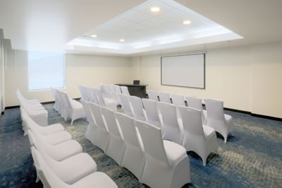 Blue Room with rows of chairs, projector screen & presentation table for event space in San Jose Costa Rica at D Sabana Hotel