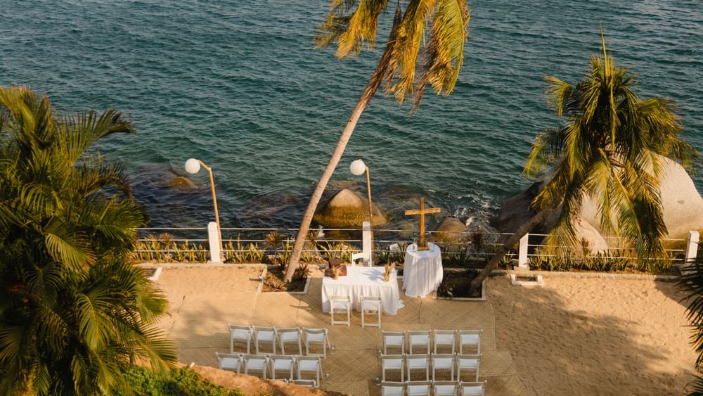 Camino Real Outdoor beach wedding ceremony setup with white chairs and ocean views at Camino Real Acapulco Diamante