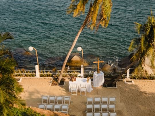 Camino Real Outdoor beach wedding ceremony setup with white chairs and ocean views at Camino Real Acapulco Diamante