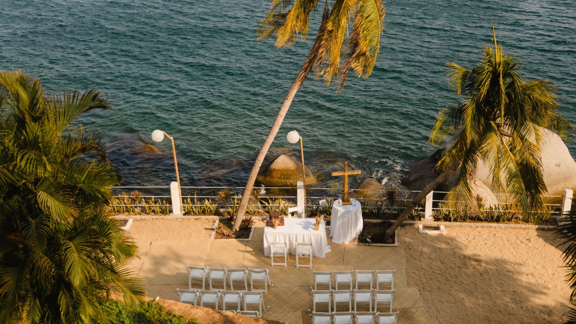 Camino Real Outdoor beach wedding ceremony setup with white chairs and ocean views at Camino Real Acapulco Diamante