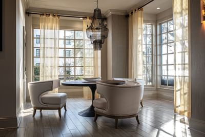 Bright seating area with curved white chairs and elegant window treatments at The White House Hotel