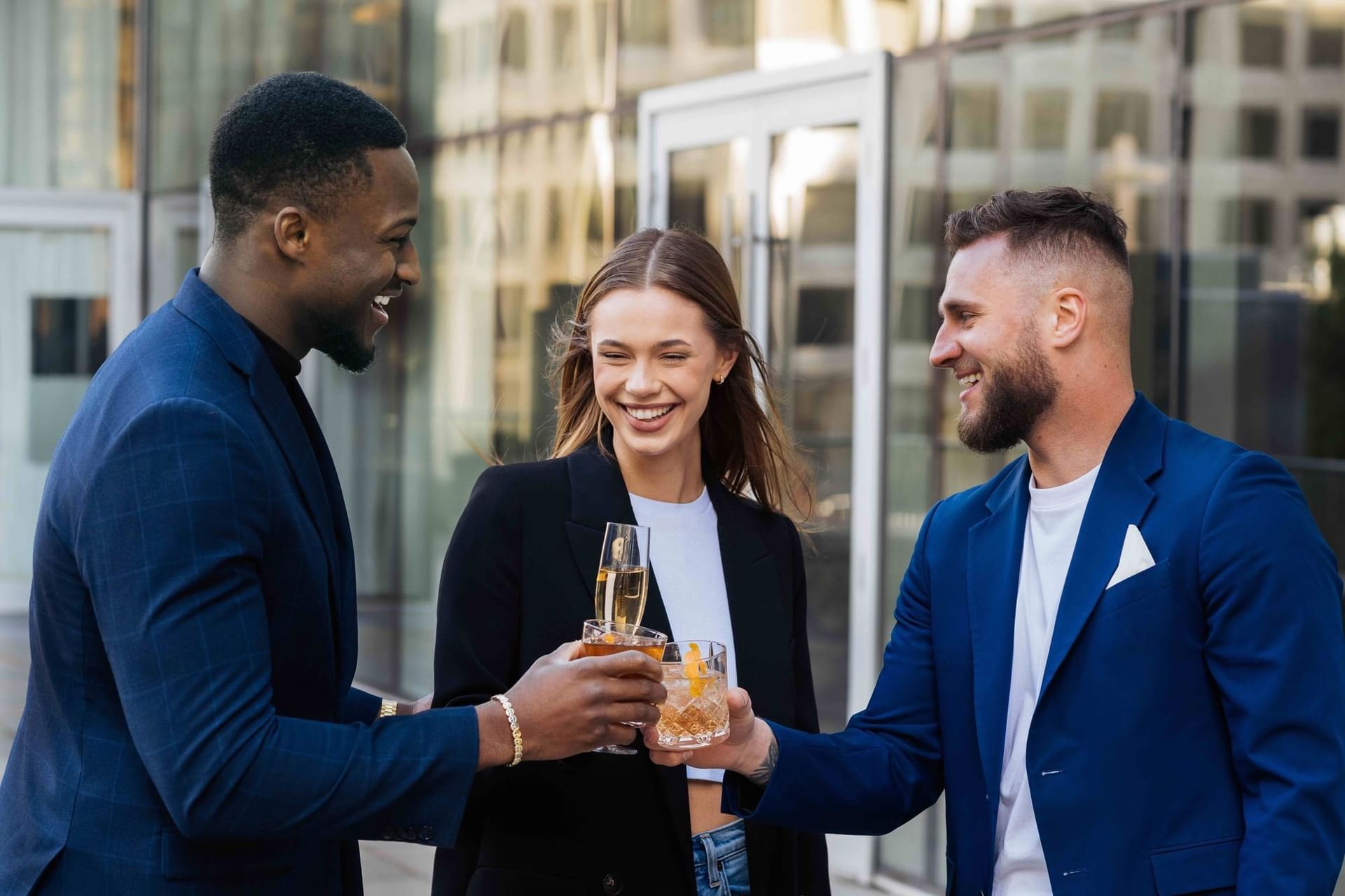 Two men and a woman holding drinks and laughing outside a building at Paradox Vancouver