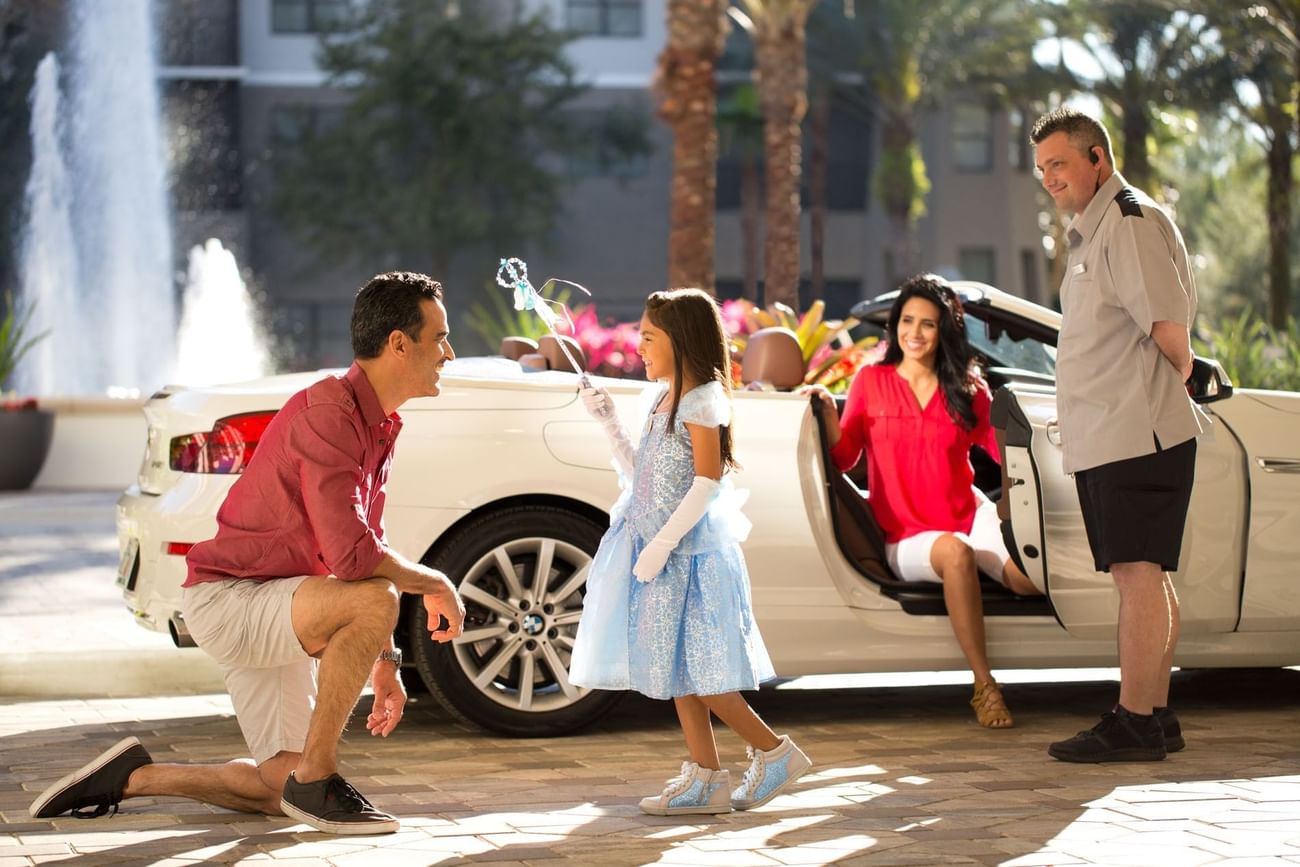 Child in a fairy costume plays with a bubble wand near an adult crouching by a car in Disney's Blizzard Beach at The Grove Resort & Water Park