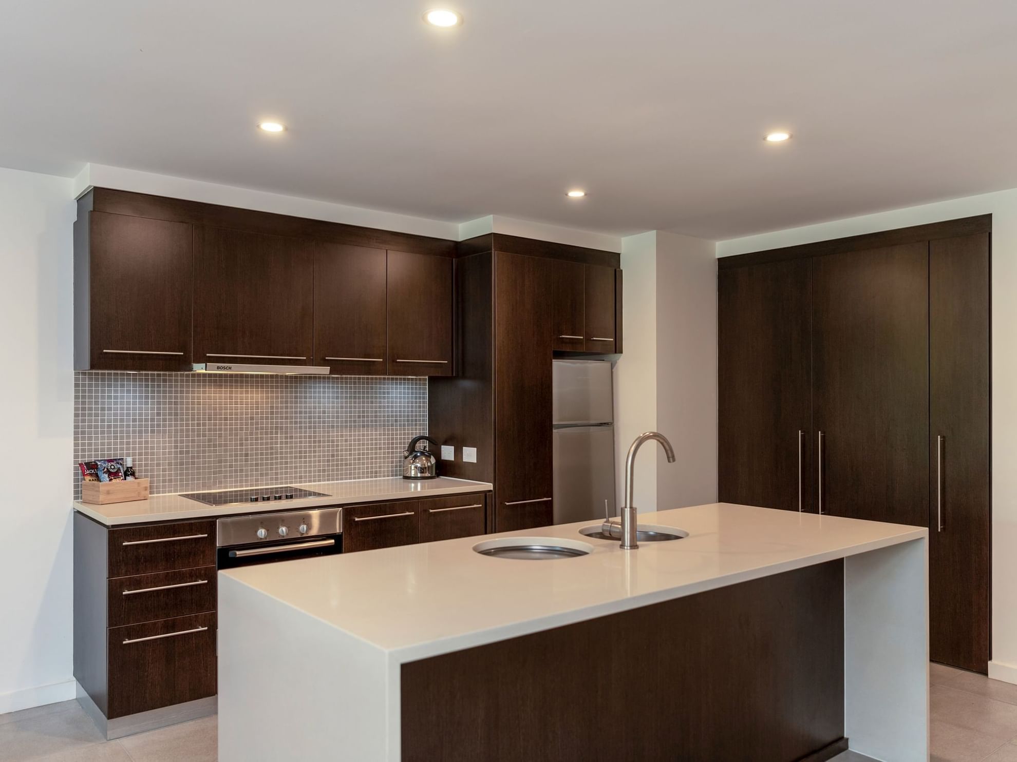 Kitchen with dark wood cabinets & stainless steel appliances at Pullman Port Douglas Sea Temple Resort & Spa