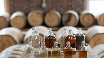 Several small bottles of Jameson whiskey on a table surrounded by barrels.