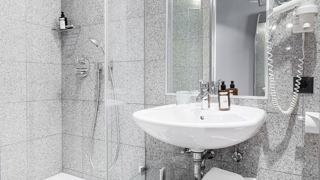 Bathroom vanity with sink and mirror in Classic Single Room at Titanic Comfort Kurfürstendamm