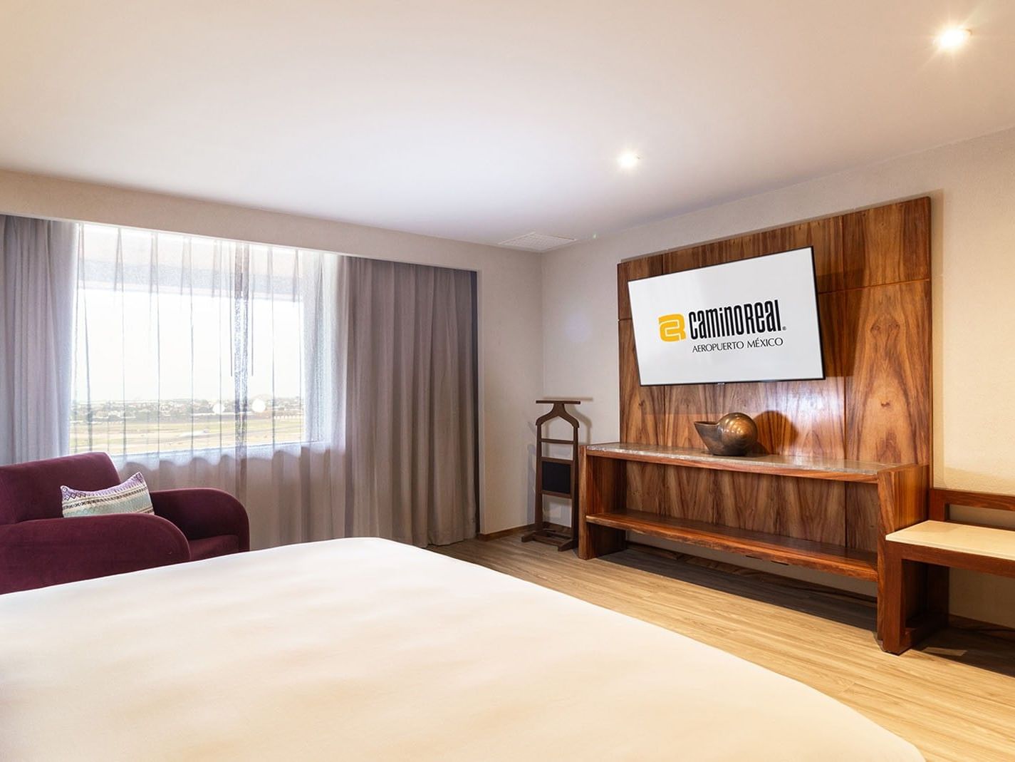 Suite Master King con cama grande, sillón, TV y vistas en Camino Real Aeropuerto México, Ciudad de México.