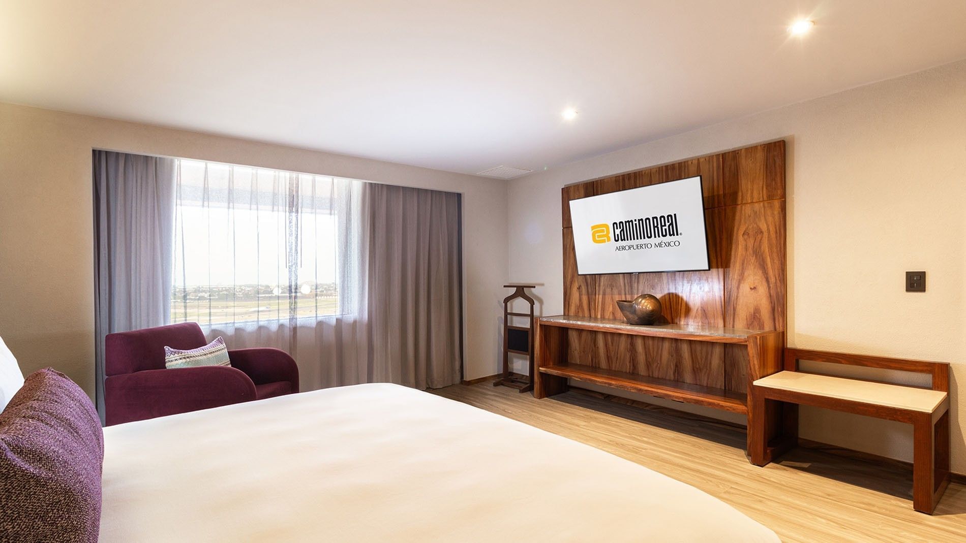 Suite Master King con cama grande, sillón, TV y vistas en Camino Real Aeropuerto México, Ciudad de México.