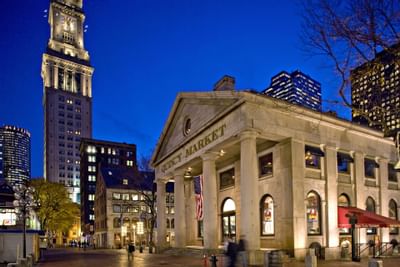 quincy market at night with boston skyline