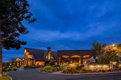 An evening exterior view of the main entrance to the Lake Placid Club Grandview lodge with a dramatic dark blue sky