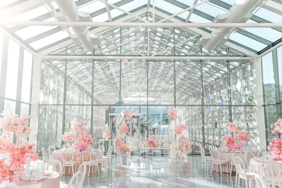 Elegant wedding setup with pink floral decor in New Fort Hall with a transparent ceiling at Hotel X Toronto