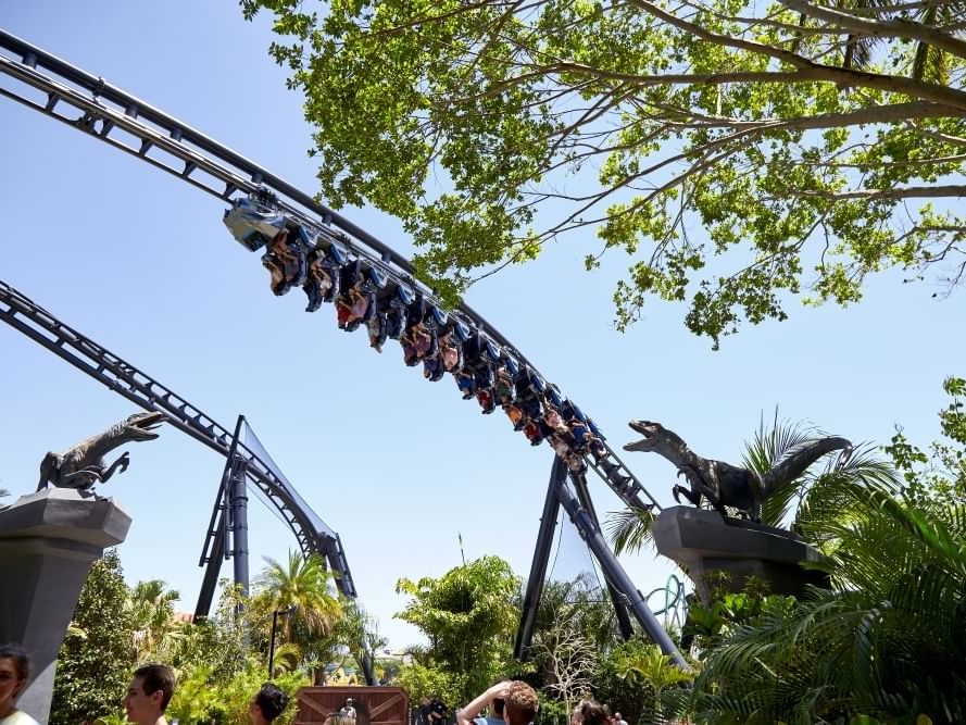 Roller coaster ride with dinosaur statues at Universal Parks & Resorts Vacation Package.