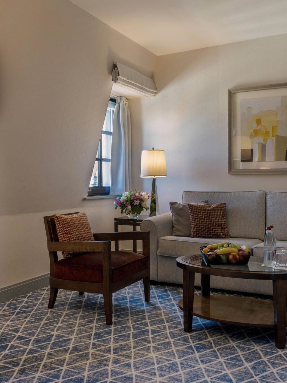 Premium Deluxe Room living room with sofa under hanging wall art and floor lamp at Warwick Grand Place Brussels