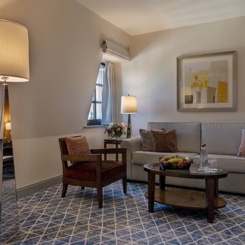 Premium Deluxe Room living room with sofa under hanging wall art and floor lamp at Warwick Grand Place Brussels