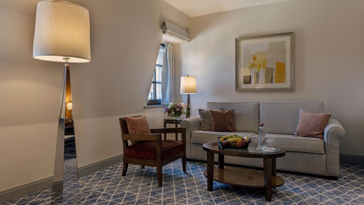 Premium Deluxe Room living room with sofa under hanging wall art and floor lamp at Warwick Grand Place Brussels