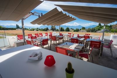Outdoor restaurant terrace with red chairs and white tables at Starling Hotel Lausanne