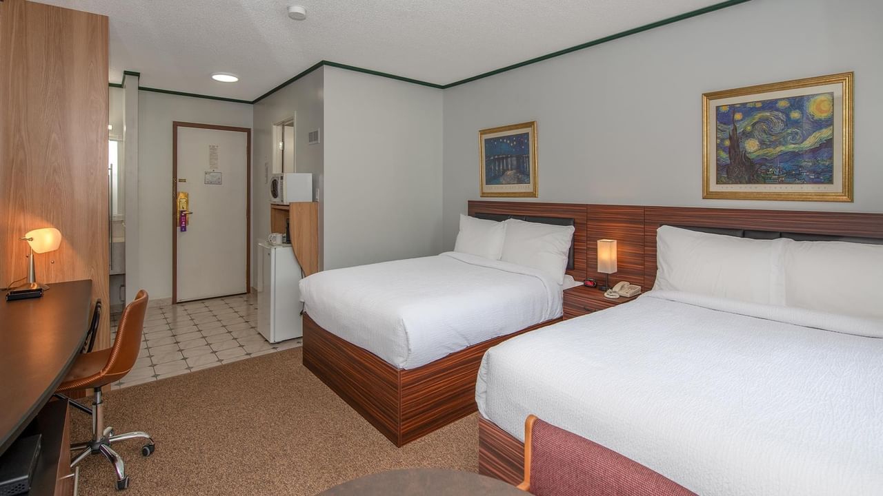 guest room with two queen beds, desk and framed artwork at Coast Whitecourt Hotel