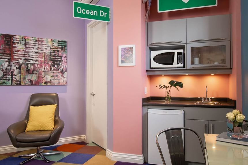 Kitchenette, work desk with fresh flowers & comfy chair in King Superior South beach at Retro Suites Hotel