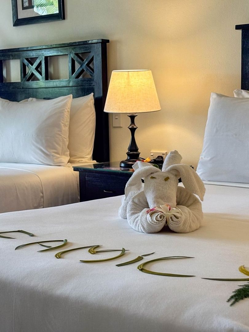 Two beds with elephant towel art and frangipani flowers at The Naviti Resort in Korolevu.