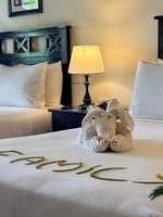 Two beds with elephant towel art and frangipani flowers at The Naviti Resort in Korolevu.