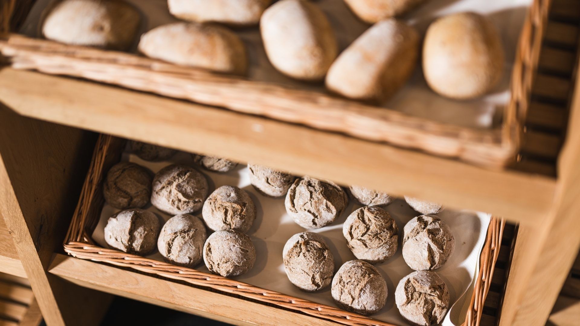 Holzregal mit zwei Körben voller frischem Gebäck bei Falkensteiner Hotel Falkensteinerhof