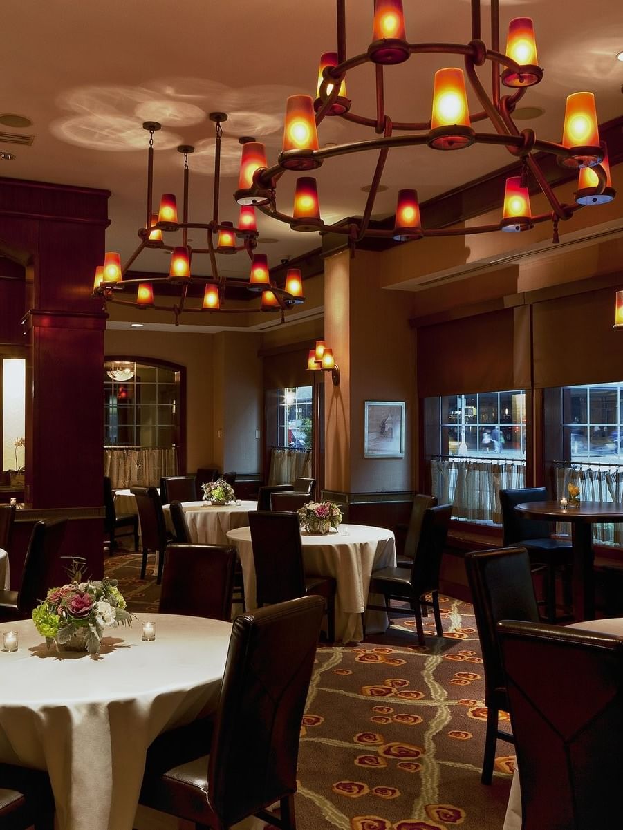 Davies Meeting Room featuring round tables with white cloths & dark chairs and hanging chandeliers at Warwick New York