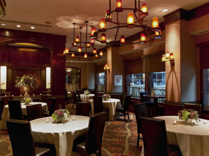 Davies Meeting Room featuring round tables with white cloths & dark chairs and hanging chandeliers at Warwick New York