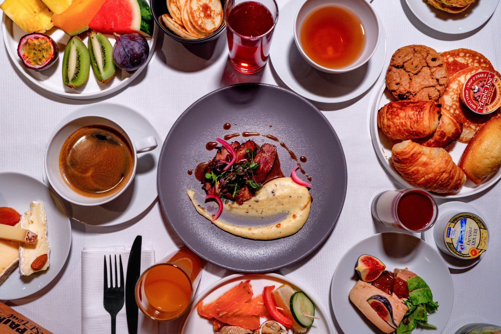 Overhead breakfast spread with pastries, coffee & fruit surrounding a meat dish on plate at Restaurant, Bar & Terrace Le W