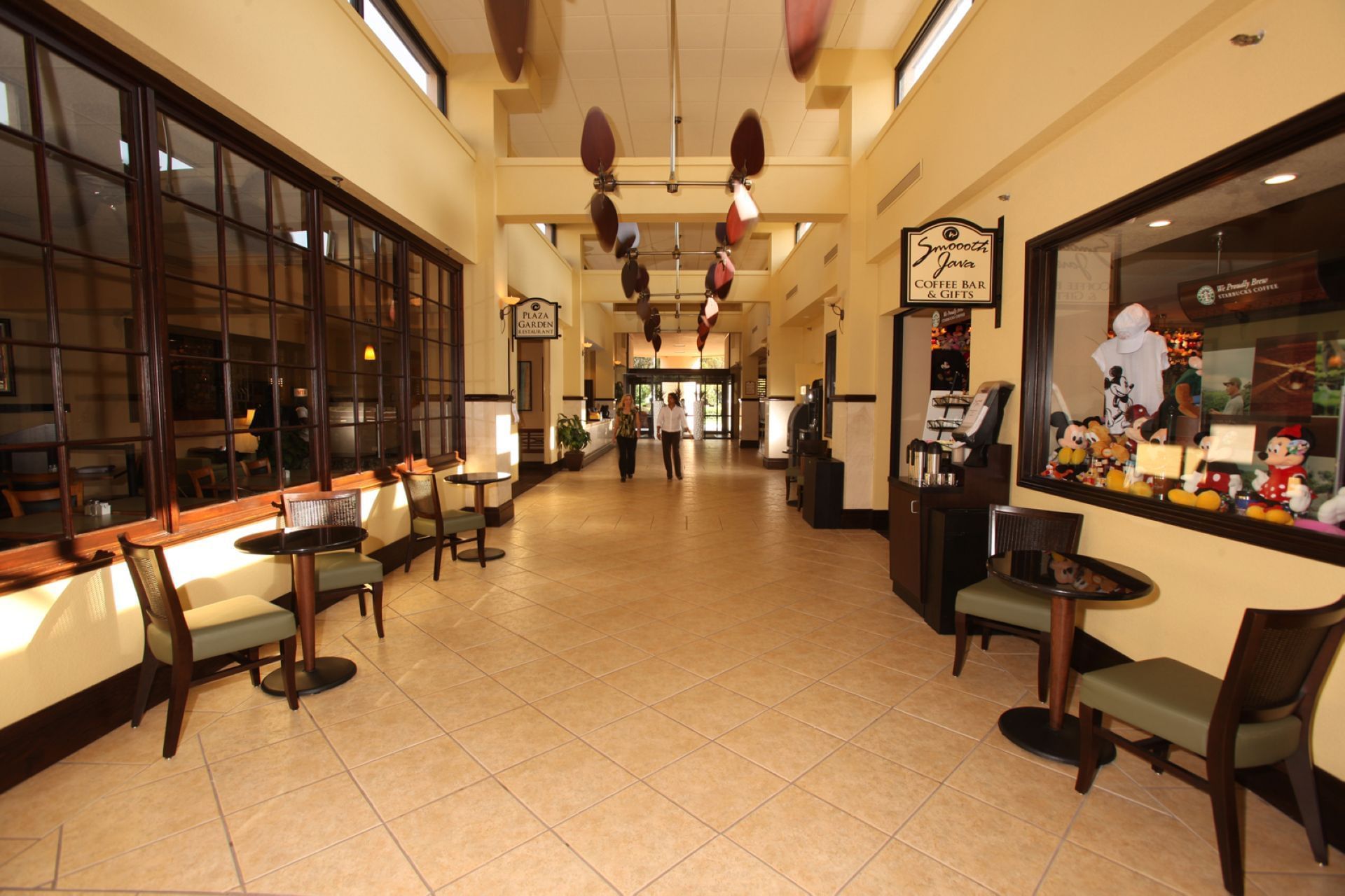 Bright hotel corridor with cafe display and dining tables near Smooth java and gift shop at Rosen Inn at Pointe Orlando