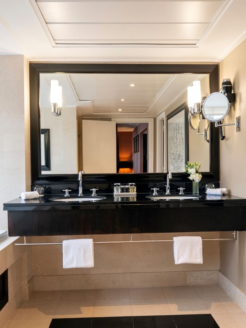 Une salle de bains luxueuse avec baignoire, double vasque et grand miroir au Warwick Champs-Élysées Paris.