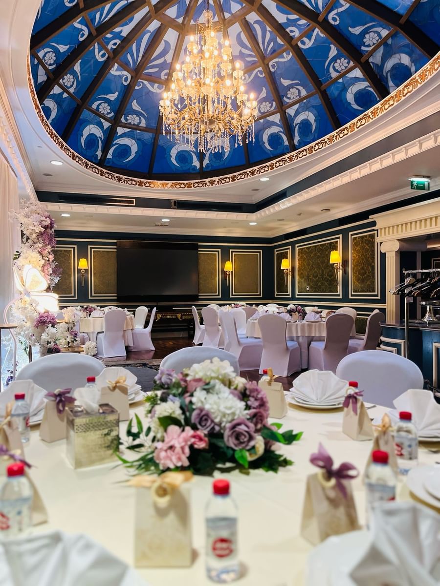 Elegantly set dining room with chandelier and floral centerpieces at Warwick Doha الدوحة