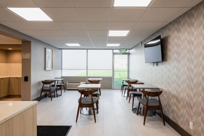 Brightly lit dining area at Garden Executive Hotel with modern seating, TV, and luxury hotel amenities