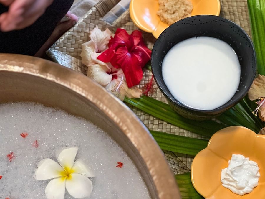 Bowl of milk, scrub, and flowers on table at The Naviti Resort - Fiji.