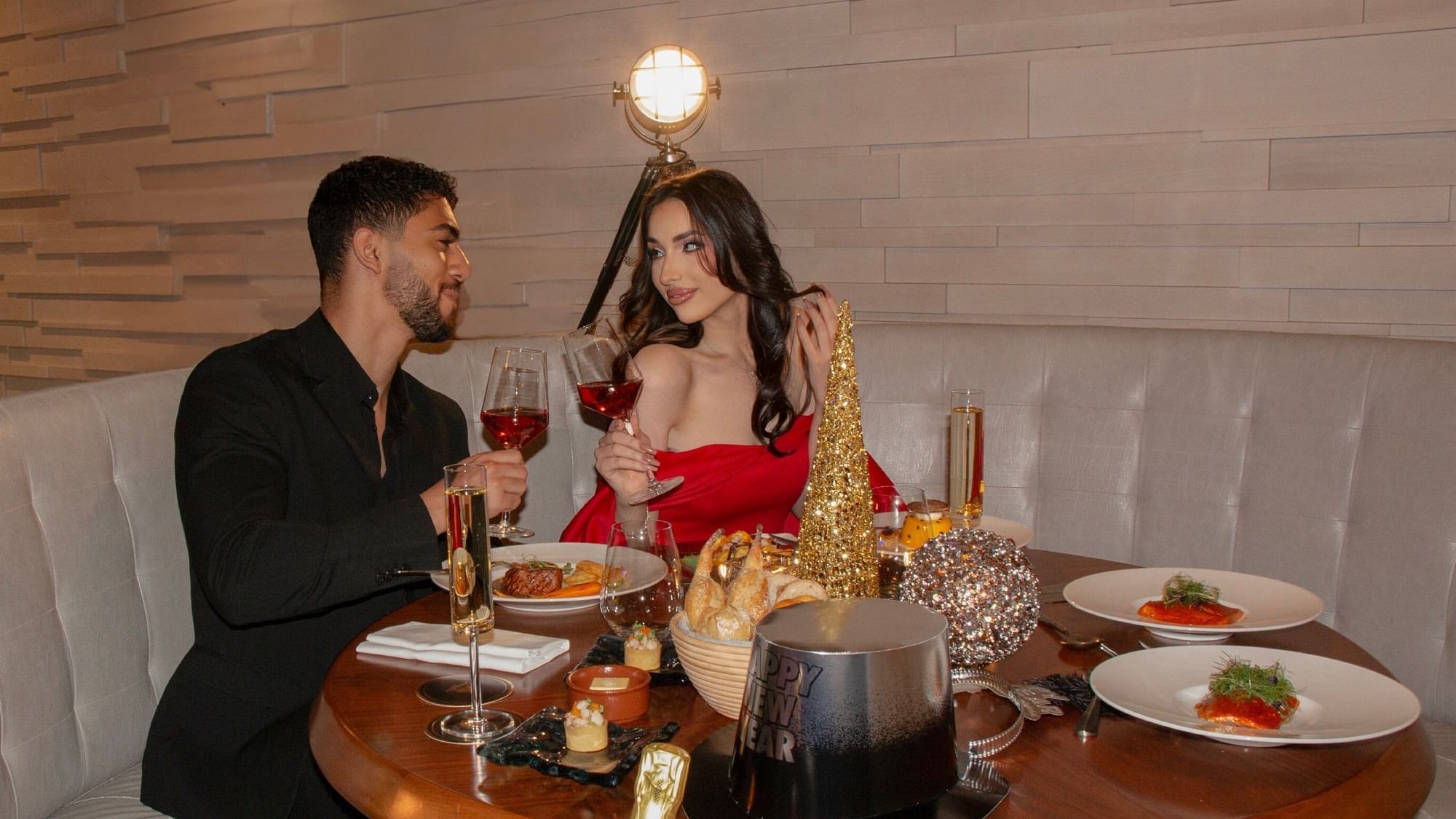 Couple enjoys a romantic dinner surrounded by elegant dishes, decors and champagne glasses at Paramount Hotels