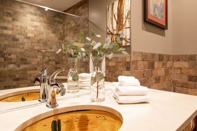 Bathroom vanity with large mirror & towels in King Premiere Wild West at Retro Suites Hotel