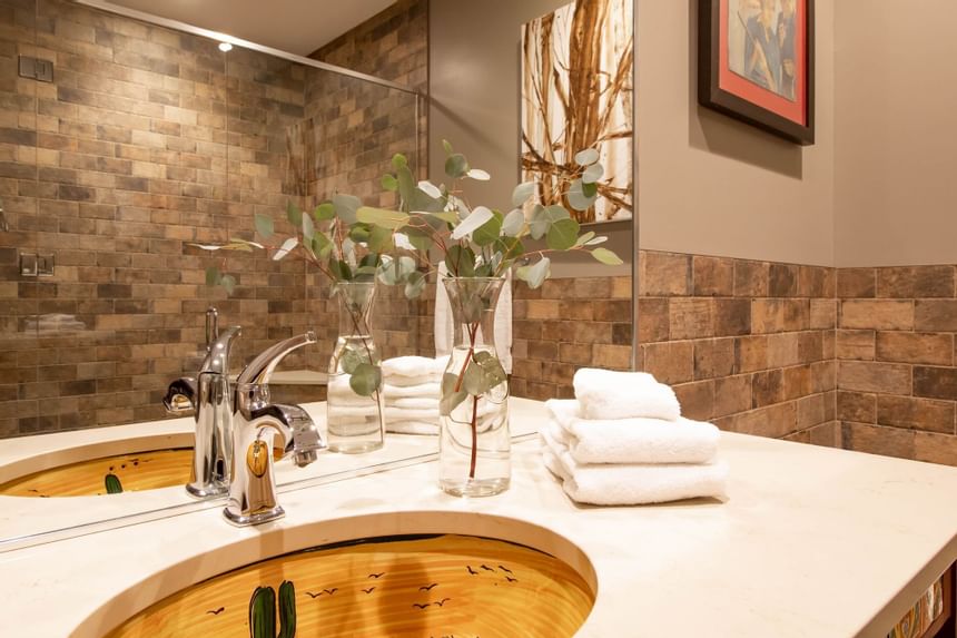 Bathroom vanity with large mirror & towels in King Premiere Wild West at Retro Suites Hotel